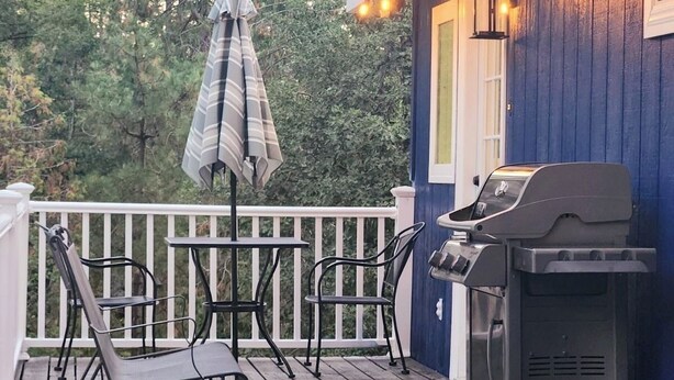 A wooden deck with outdoor furniture, a barbecue grill, and string lights.
