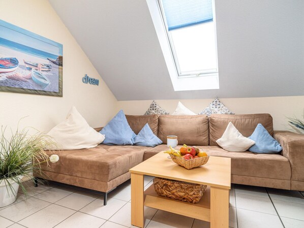 Ein gemütliches Wohnzimmer mit einem braunen Sofa, einem Holztisch und einem Bild von Booten an der Wand.