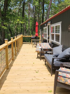 A wooden deck with outdoor seating, a red umbrella, and a building with a 'Welcome' sign. - Majestic Woods Cabin 1 - Peaceful and private (Logan)