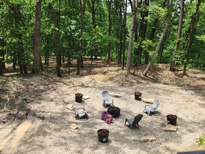 An outdoor seating area with chairs and planters, surrounded by trees. - Majestic Woods Cabin 1 (Logan)
