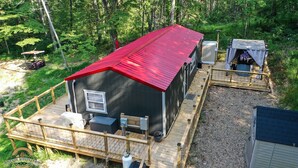Een chalet met een rood dak, een terras en een klein voortuintje.