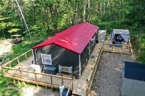 A cabin with a red roof, a deck, and a small porch.