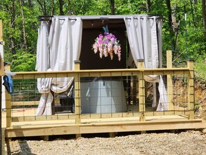 A wooden structure with a covered area, a hanging floral arrangement, and a metal tank. - Majestic Woods Cabin 1 (Logan)