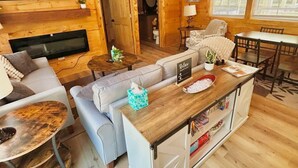 A cozy cabin interior with a living room, dining area, and a bathroom. - Majestic Woods Cabin 1 (Logan)