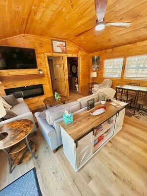 A cozy cabin interior with a living room, dining area, and a bathroom. - Majestic Woods Cabin 1 (Logan)