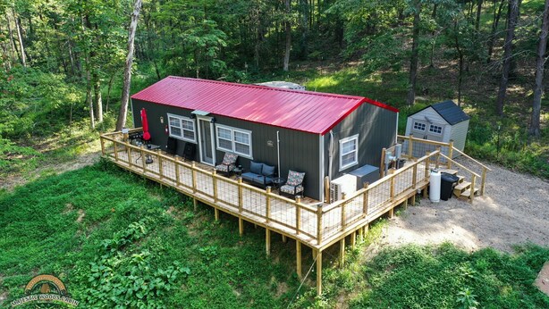 A cabin with a red roof, a deck, and outdoor seating. - Majestic Woods Cabin 1 (Logan)