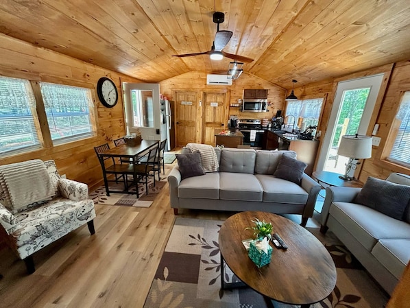 A cozy cabin interior with a dining area, sofa, and a kitchen.
