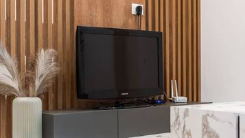 Un téléviseur Samsung fixé sur un mur en bois, avec une prise de courant blanche située juste au-dessus.