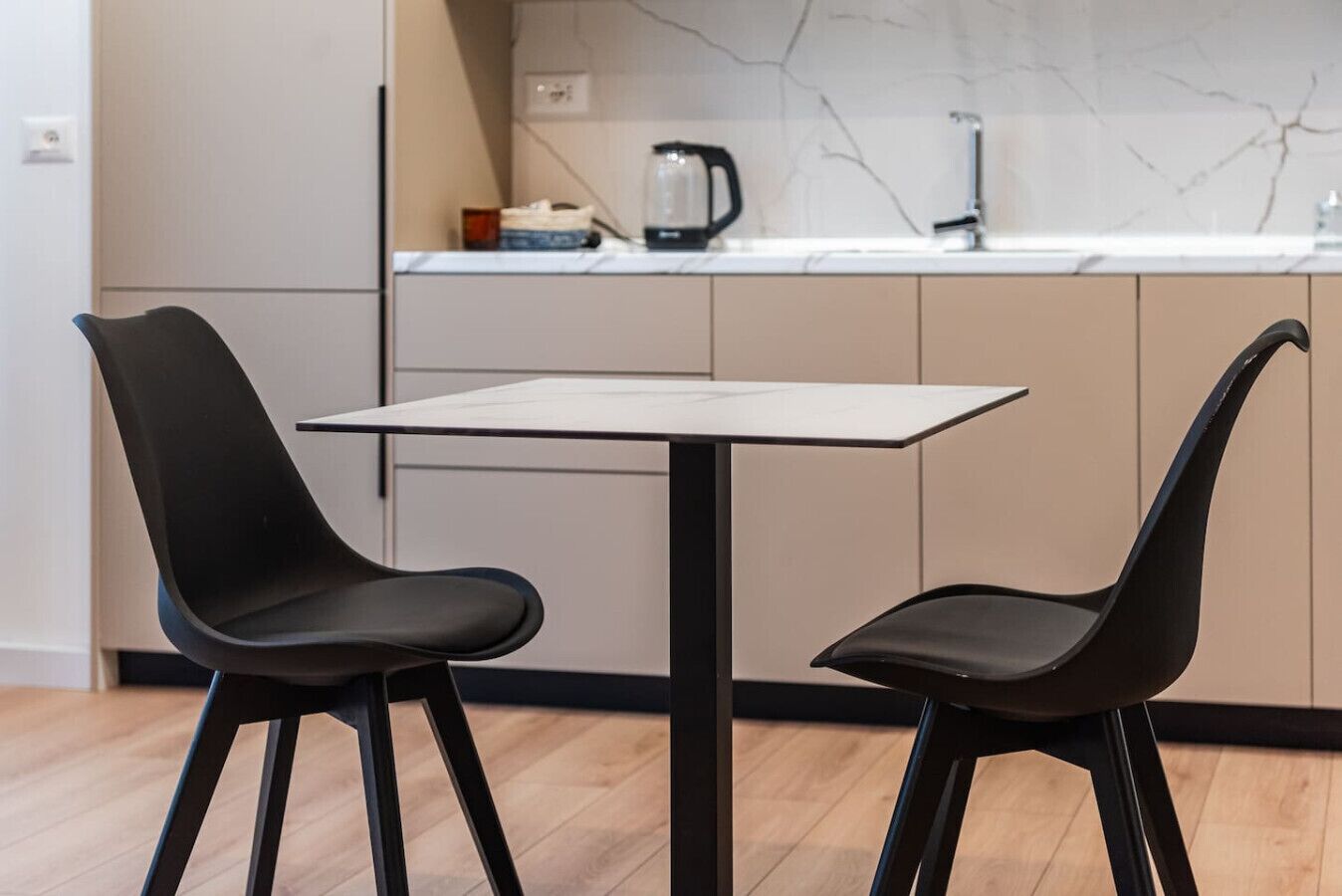 A modern kitchen with two black chairs and a white table.