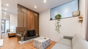A modern living room with a TV, sofa, coffee table, and decorative plants.