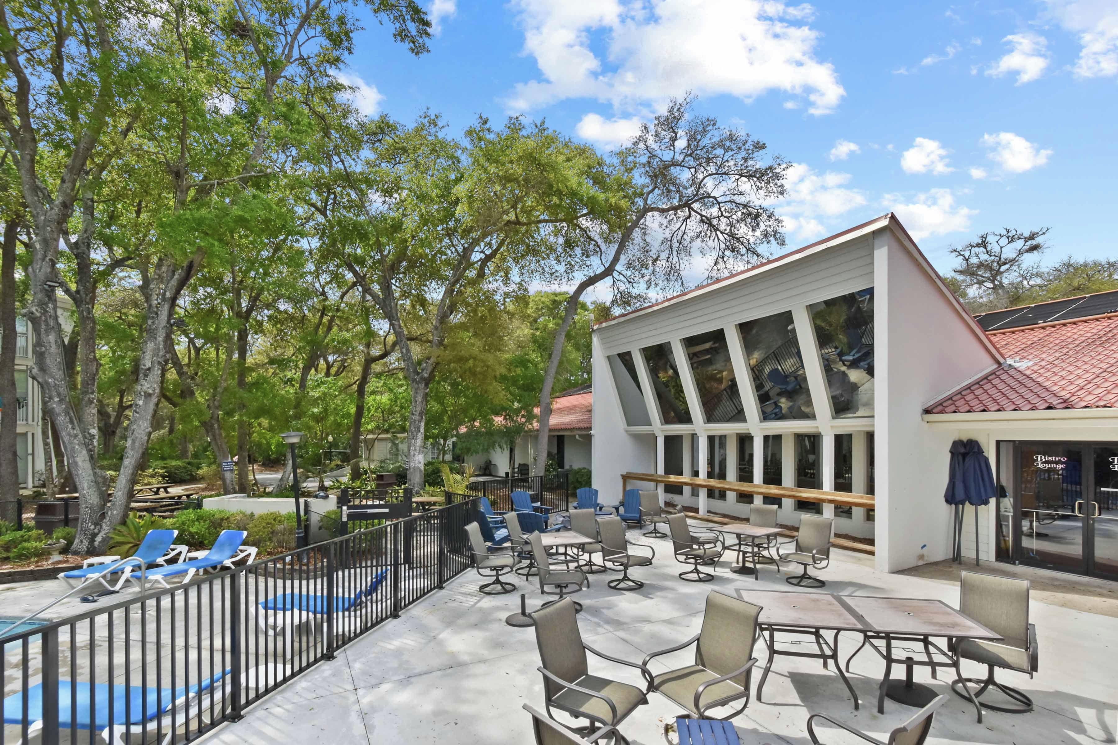An outdoor patio with seating, a pool, and a building with large windows.