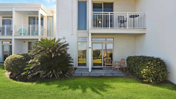 Un immeuble résidentiel à deux étages, doté de balcons, d’une pelouse bien entretenue et d’un petit espace patio.