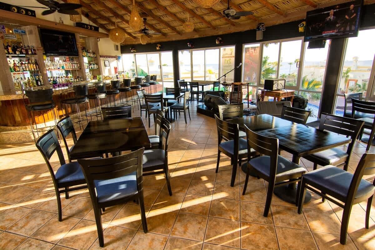 A restaurant with outdoor seating, a bar area, and large windows.