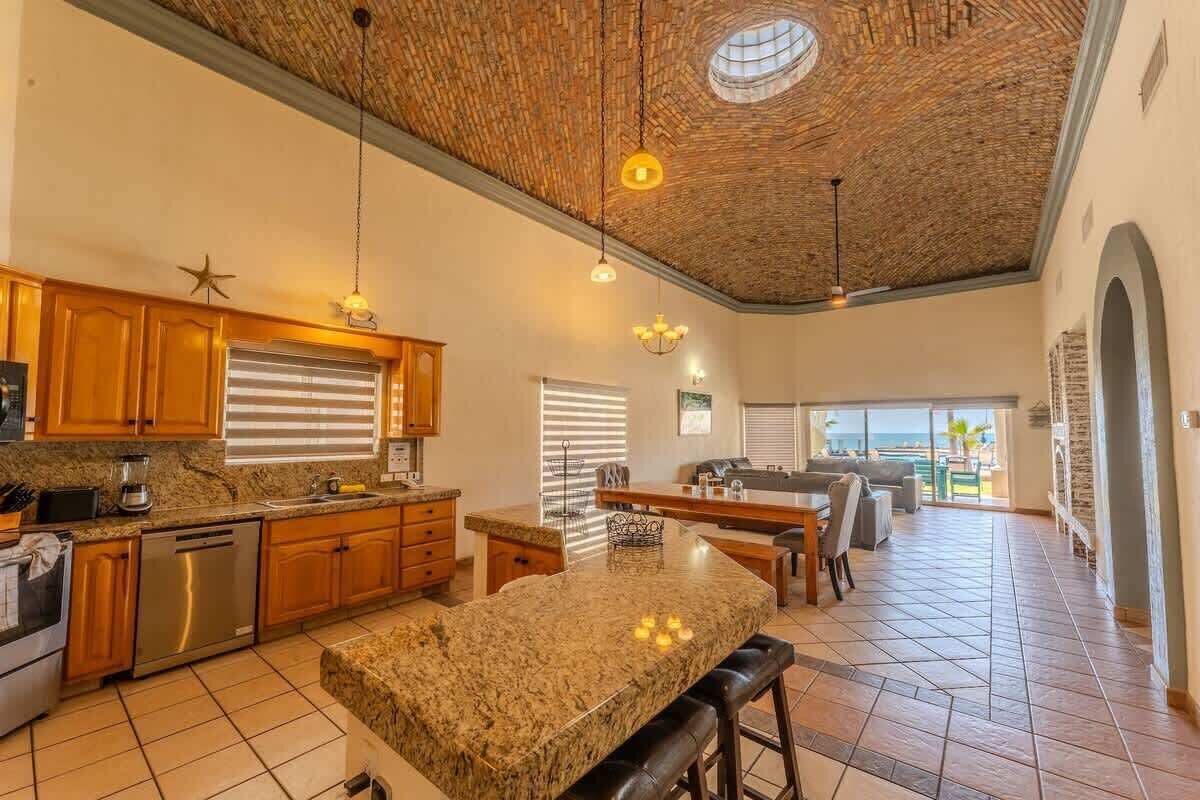 A spacious kitchen with granite countertops, wooden cabinets, and a large island.