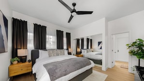 A modern bedroom with a large bed, bedside tables, a ceiling fan, and a mirror. - New 2 En Suite Bedrooms, Balboa Park,  Lux, 85" TV, Parking! (San Diego)