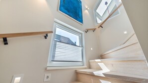 A modern staircase with wooden steps and a view of the outside through a window with blinds. - Dünenloft - Relax and enjoy in the Dünenloft: your perfect vacation apartment on the (Rantum)