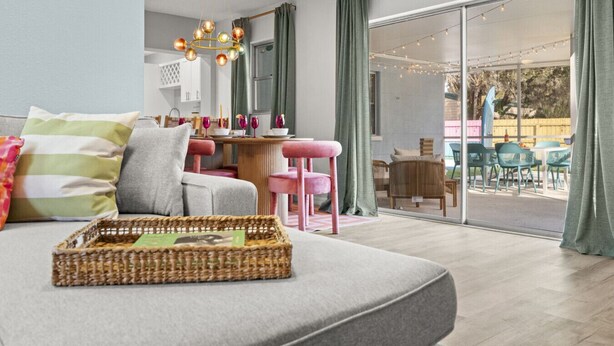 A modern living room with a grey sofa, a wicker tray, and a dining area with a table and chairs. - Clearwater Pickleball,  Heated Pool, MiniGolf Oasis! 15 min to beach (Clearwater)