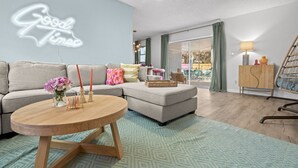 A modern living room with a sofa, a coffee table, and a neon sign. - Clearwater Pickleball,  Heated Pool, MiniGolf Oasis! 15 min to beach (Clearwater)
