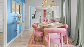 A dining area with a round table, pink chairs, and a chandelier. - Clearwater Pickleball,  Heated Pool, MiniGolf Oasis! 15 min to beach (Clearwater)