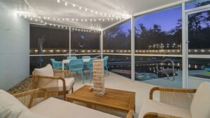 An outdoor patio with wicker furniture, a pool, and string lights. - Clearwater Pickleball,  Heated Pool, MiniGolf Oasis! 15 min to beach (Clearwater)