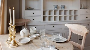 Une table à manger dressée avec de la vaisselle blanche, des verres et un chandelier doré.