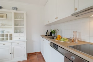 A kitchen with white cabinetry, a wooden countertop, and a stainless steel sink.