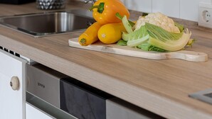 Une cuisine avec un évier en acier inoxydable, un plan de travail en bois et une plante en pot.
