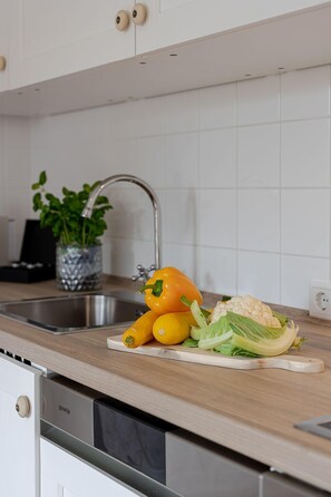 A kitchen with a stainless steel sink, a wooden countertop, and a potted plant.