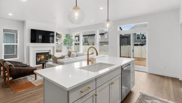 Una cocina moderna con una isla grande, armarios blancos e iluminación colgante.
