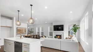 Una cocina moderna con armarios blancos, una isla central e iluminación colgante.