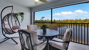 A balcony with a round table, chairs, and a hanging chair.