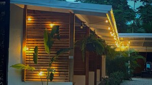 Un bâtiment moderne doté d’un espace extérieur couvert, de lambris en bois et de guirlandes lumineuses.