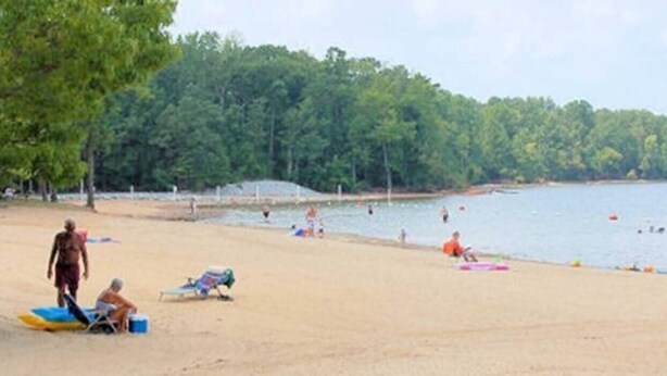 Ein Strand mit badenden und sonnenbadenden Personen.