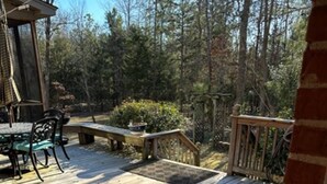 Eine Holzterrasse mit Tisch und Stühlen, umgeben von Bäumen.