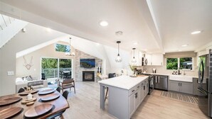 A spacious kitchen with a large island, modern appliances, and a view to an outdoor deck. - Lake View Home, 2 Spacious Decks, Fire Pit, WiFi, On Sight Casita Option Avail. (Lake Arrowhead)