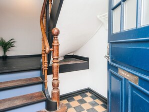 A staircase with wooden balusters and a blue door with a nameplate.