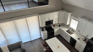 A modern kitchen with white cabinets, a black stove, and a marble island. - RIVERFRONT  NEW 4-bedroom house with WiFi and AC in Calico Rock (Calico Rock)