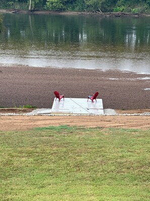 A riverside area with a concrete platform and two red chairs facing the water. - RIVERFRONT  NEW 4-bedroom house with WiFi and AC in Calico Rock (Calico Rock)