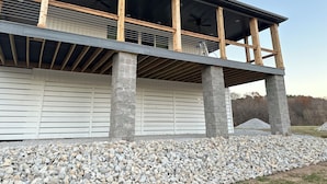 A modern house with a covered porch, stone pillars, and a gravel driveway. - RIVERFRONT  NEW 4-bedroom house with WiFi and AC in Calico Rock (Calico Rock)