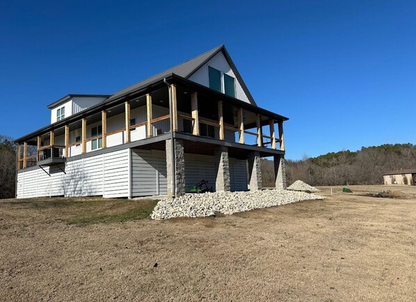A two-story house with a balcony, a stone foundation, and a grassy yard. - RIVERFRONT  NEW 4-bedroom house with WiFi and AC in Calico Rock (Calico Rock)