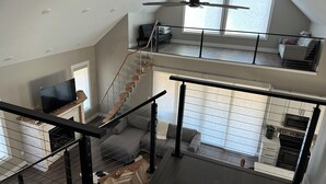 A multi-level living space with a staircase, a fireplace, a kitchen area, and a balcony with a view. - RIVERFRONT  NEW 4-bedroom house with WiFi and AC in Calico Rock (Calico Rock)