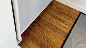 Un panel blanco con textura y diseño de malla, suelo de madera y pared blanca.