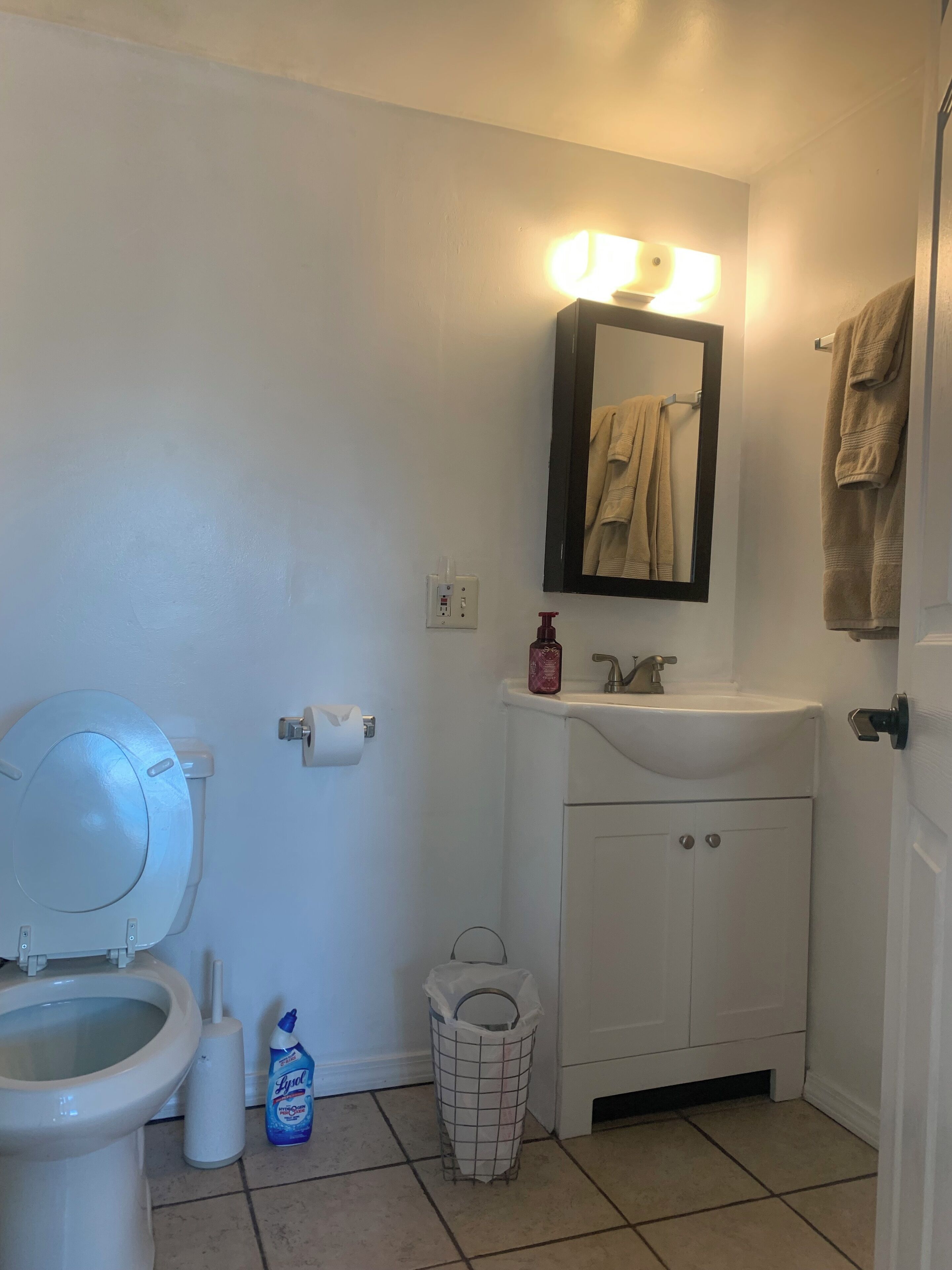 Une salle de bain équipée de toilettes, d’un lavabo, d’un miroir et d’un porte-serviettes.