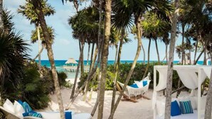 Une plage avec des cabanas blanches et des hamacs, des palmiers, et une vue sur l’océan.