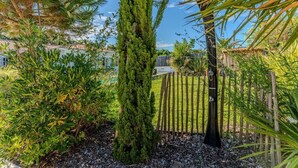 A garden with a tall coniferous tree, a wooden fence, and a clear sky. - Family home 2 steps from the Bassin (Gujan-Mestras)