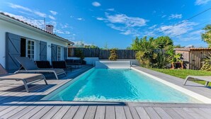 A rectangular swimming pool with a wooden deck, surrounded by a wooden fence and greenery. - Family home 2 steps from the Bassin (Gujan-Mestras)