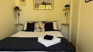 A neatly made bed with a black and white patterned bedspread, two decorative pillows, and a folded towel on top. - Off grid tiny house bush escape (Nar Nar Goon North)
