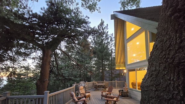 A wooden deck with outdoor furniture, a railing, and a building with large windows.