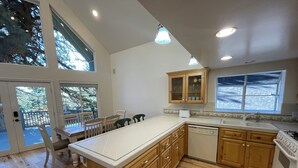 A spacious kitchen with wooden cabinets, a large island, and a view of the outdoors through the windows.