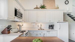 Een moderne keuken met witte kastjes, een houten aanrecht, een roestvrijstalen spoelbak en een koffiezetapparaat.